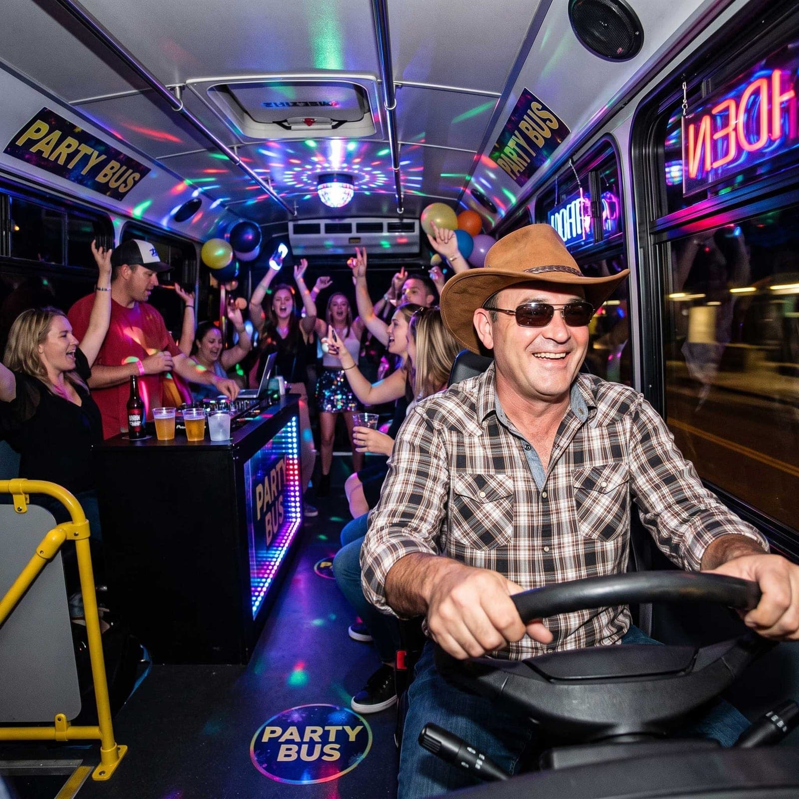 Cowboy Mick at the wheel of a party bus, with the group dancing behind him